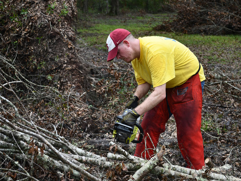 Trevor Bryan from the Tallahassee Florida Stake works with a chainsaw.
